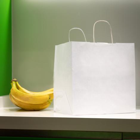 Bolsas de comida para llevar al lado de unos plátanos